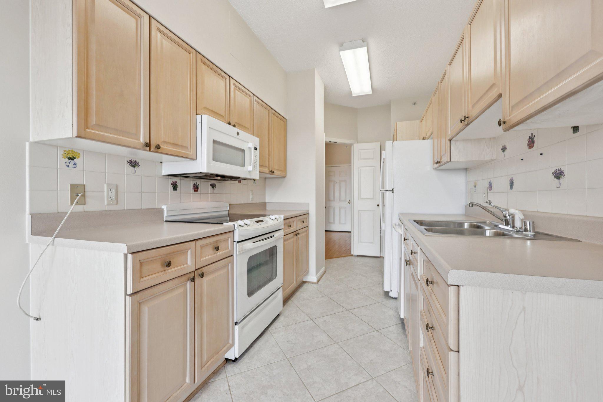 19375 Cypress Ridge Terrace, Unit 1111 Leesburg, VA 20176 - Photo 10 of 35 a kitchen with cabinets and white appliances