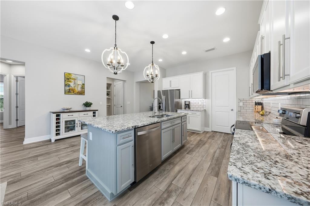 3344 Pilot Circle Naples, FL 34120 - Photo 4 of 50 a large kitchen with stainless steel appliances granite countertop a stove oven and a large island with wooden floor