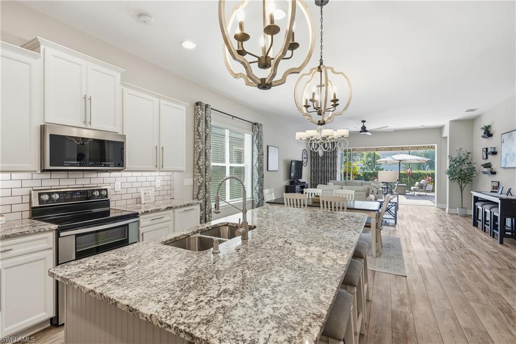3344 Pilot Circle Naples, FL 34120 - Photo 7 of 50 a kitchen with stainless steel appliances granite countertop a stove oven and a dining table with the kitchen view
