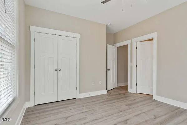 a view of an empty room with wooden floor and a window