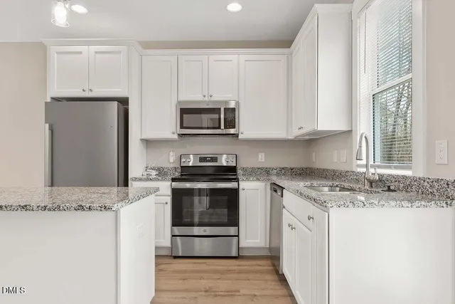 a kitchen with stainless steel appliances granite countertop a stove a microwave and a refrigerator
