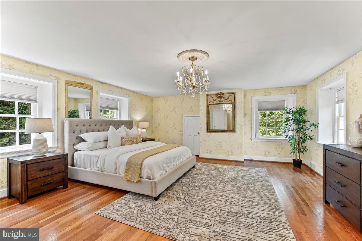 716 Old Gulph Road Bryn Mawr, PA 19010 - Photo 24 of 58 a spacious bedroom with a large bed and a chandelier