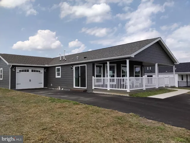 a front view of a house with a garden and trees