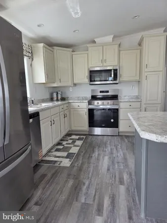 a kitchen with granite countertop a refrigerator stove top oven and sink