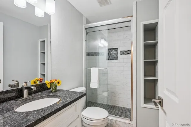 a bathroom with a granite countertop sink toilet a mirror and shower