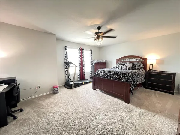 a spacious bedroom with a bed and a ceiling fan