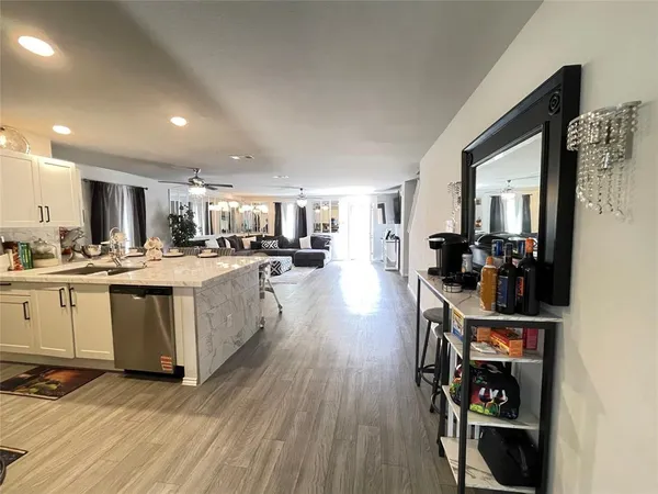 a kitchen with stainless steel appliances kitchen island granite countertop a sink cabinets and wooden floor