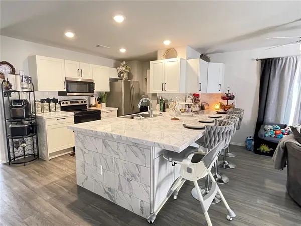 a kitchen with stainless steel appliances kitchen island granite countertop a table chairs and a refrigerator