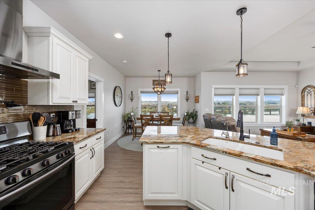 40 Bell Rapids Road Hagerman, ID 83332 - Photo 11 of 50 Kitchen with stainless steel gas range, white cabinets, light stone counters, pendant lighting, and light wood-style flooring