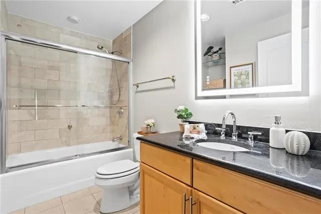 a bathroom with a granite countertop sink a toilet a mirror and shower