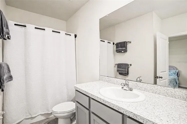 a bathroom with a granite countertop sink toilet and shower