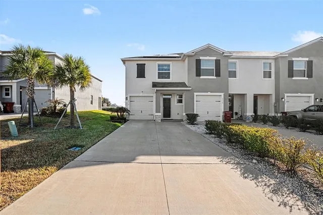 a front view of a house with a garden and palm trees