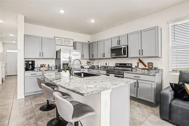 a kitchen with stainless steel appliances granite countertop a stove top oven a sink a refrigerator and white cabinets