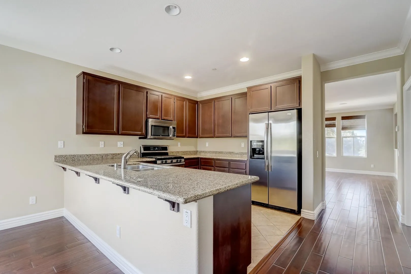 10185 Leavesly Trail Santee, CA 92071 - Photo 16 of 27 a kitchen with a refrigerator a microwave a sink and wooden floor