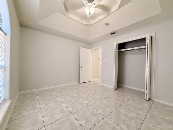 an empty room with a chandelier fan and windows