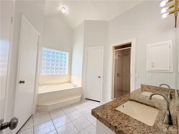 a bathroom with a granite countertop tub sink and mirror
