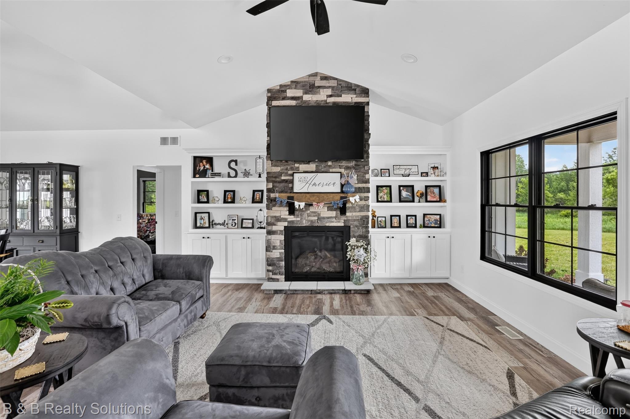 6204 Fish Lake Road North Branch, MI 48461 - Photo 7 of 79 Living area featuring a stone-clad fireplace with a built-in mantel, flanked by white built-in cabinetry and shelving