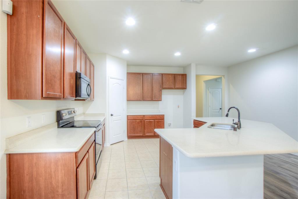 5633 Ridge Lake Drive Fort Worth, TX 76244 - Photo 7 of 23 Kitchen with range with electric cooktop, recessed lighting, an island with sink, black microwave, and wood finish cabinetry