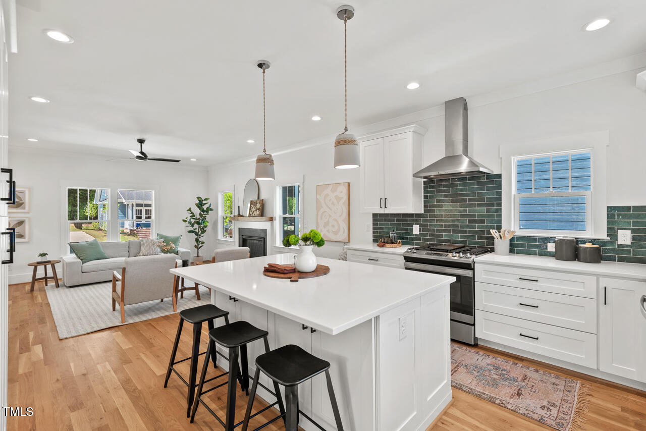 2019 James Street Durham, NC 27707 - Photo 10 of 46 a open kitchen with stainless steel appliances kitchen island a stove a refrigerator a sink a dining table and chairs with wooden floor