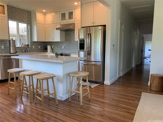 a kitchen with stainless steel appliances a dining table chairs refrigerator and sink