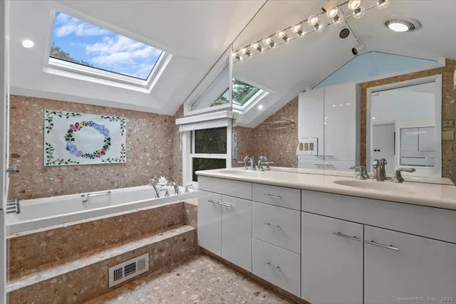 a spacious bathroom with a double vanity sink mirror and bathtub
