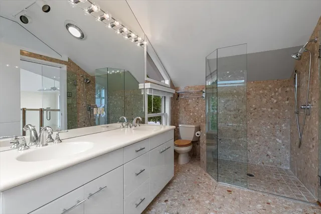 a bathroom with a double vanity sink toilet and shower