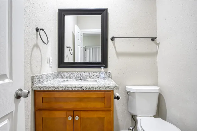a bathroom with a granite countertop toilet sink and mirror