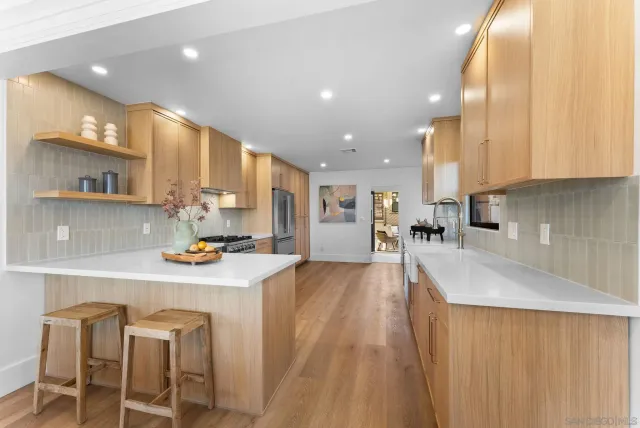 a large kitchen with stainless steel appliances a large counter top a stove and a sink
