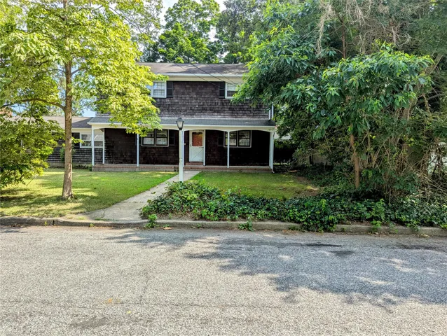 a front view of a house with a garden and trees