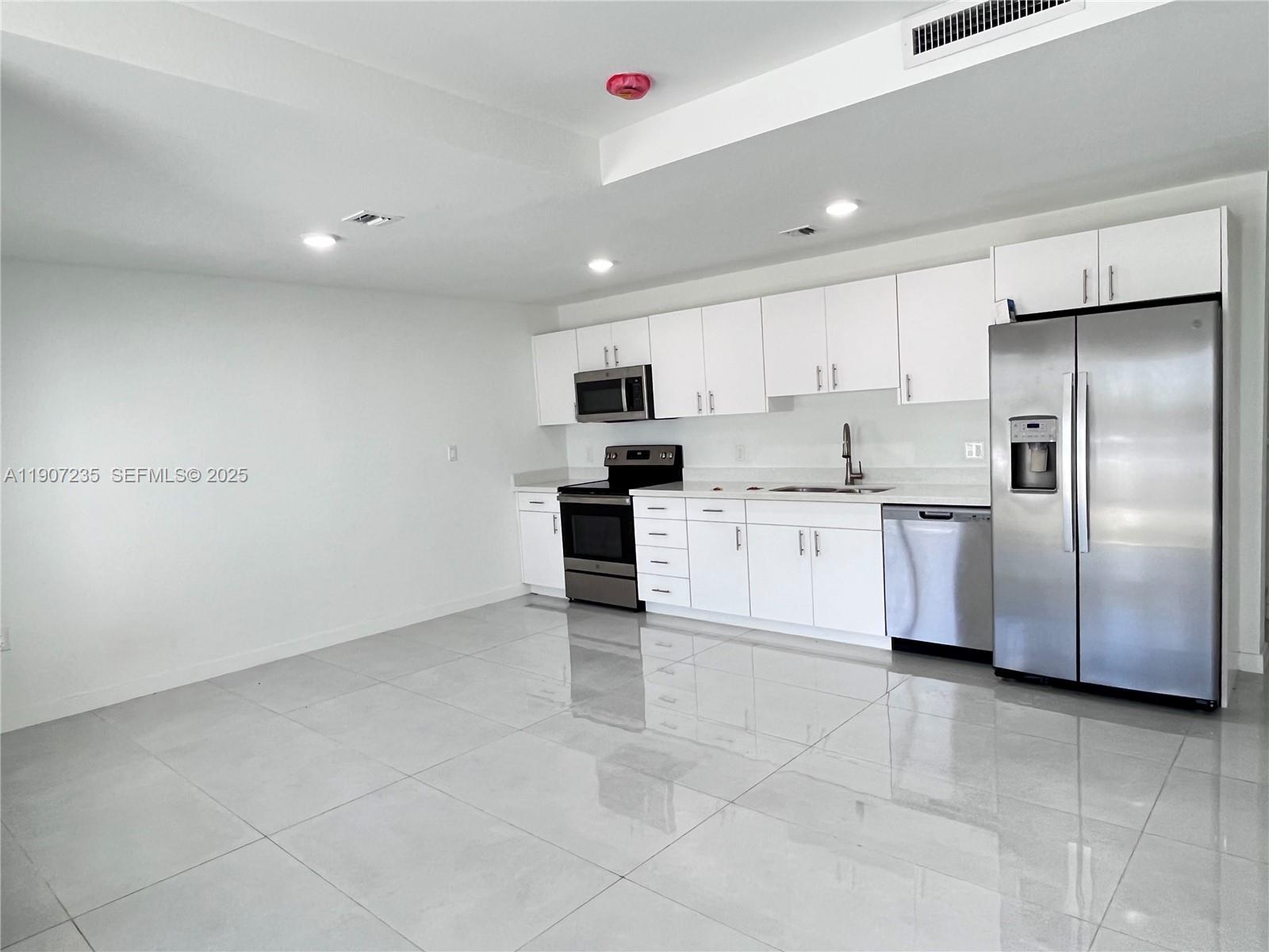 14559 Southwest 261st Street, Unit 14559 Homestead, FL 33032 - Photo 6 of 15 a kitchen with stainless steel appliances granite countertop a refrigerator sink and cabinets