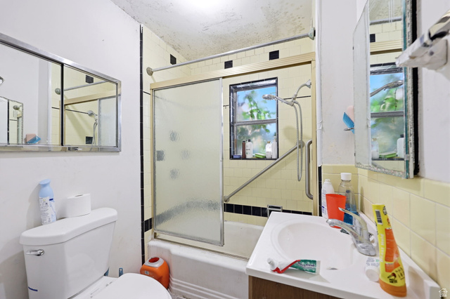 5480 South 2000th Street West Roy, UT 84067 - Photo 21 of 36 Bathroom featuring a toilet, a single vanity with a basin sink, and a shower-over-tub with a sliding glass door