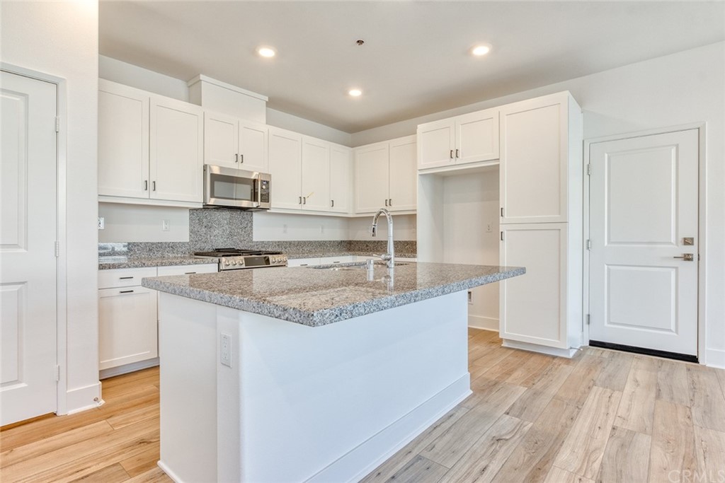 5603 Kate Way Fontana, CA 92336 - Photo 26 of 63 a kitchen with stainless steel appliances granite countertop a stove a sink and white cabinets with wooden floor