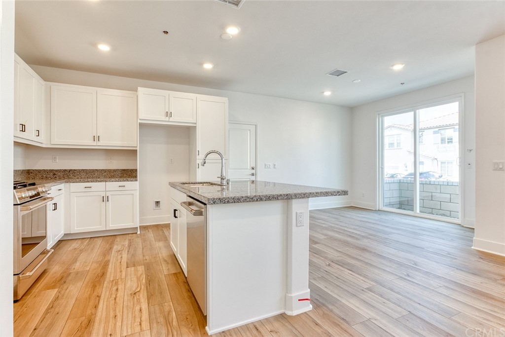 5603 Kate Way Fontana, CA 92336 - Photo 27 of 63 a kitchen with granite countertop a sink cabinets and wooden floor