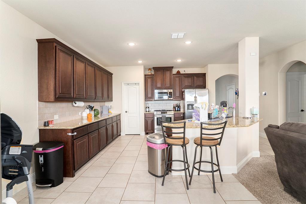 1076 Imperial Eagle Road Alvarado, TX 76009 - Photo 7 of 32 a kitchen with stainless steel appliances kitchen island granite countertop a sink and cabinets
