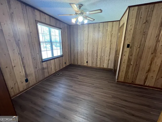 an empty room with wooden floor fan and windows