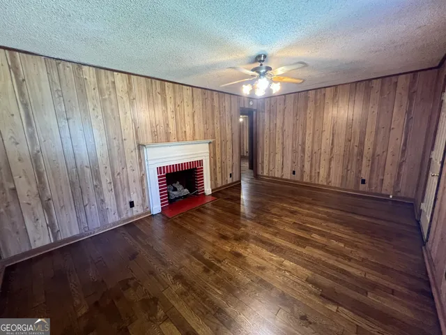 a view of an empty room with wooden floor fireplace and a window