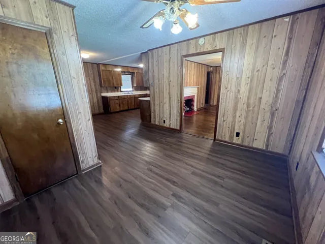 a view of a hallway and wooden floor and an empty room with wooden floor