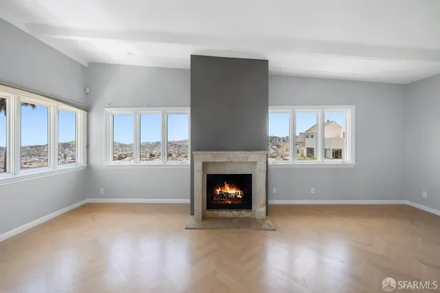 a living room with stainless steel appliances furniture a fireplace and a large window