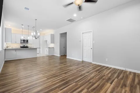 a view of empty room with wooden floor and fan