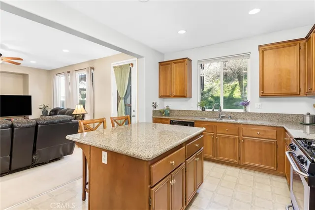 a kitchen with stainless steel appliances granite countertop a sink a stove a refrigerator a dining table and chairs