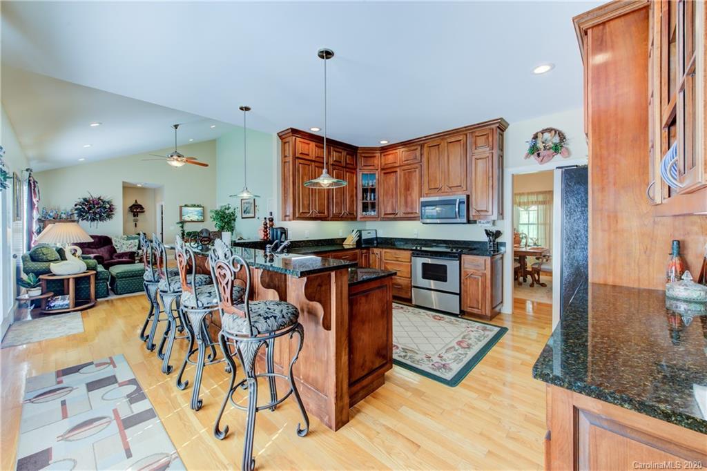 146 Pumkin Patch Road Rutherfordton, NC 28139 - Photo 15 of 48 a kitchen with stainless steel appliances granite countertop a stove top oven a sink a dining table and chairs with wooden floor