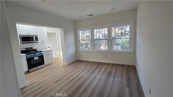 a view of an empty room with a window and wooden floor