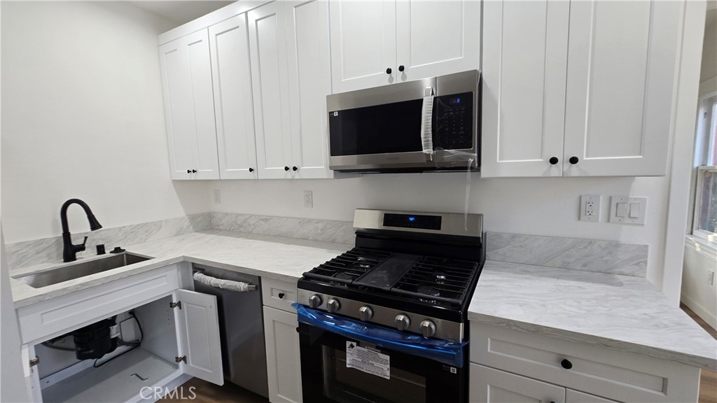 1038 Beacon Avenue, Unit 1038 Los Angeles, CA 90015 - Photo 7 of 9 a kitchen with stainless steel appliances a stove a microwave a sink and cabinets