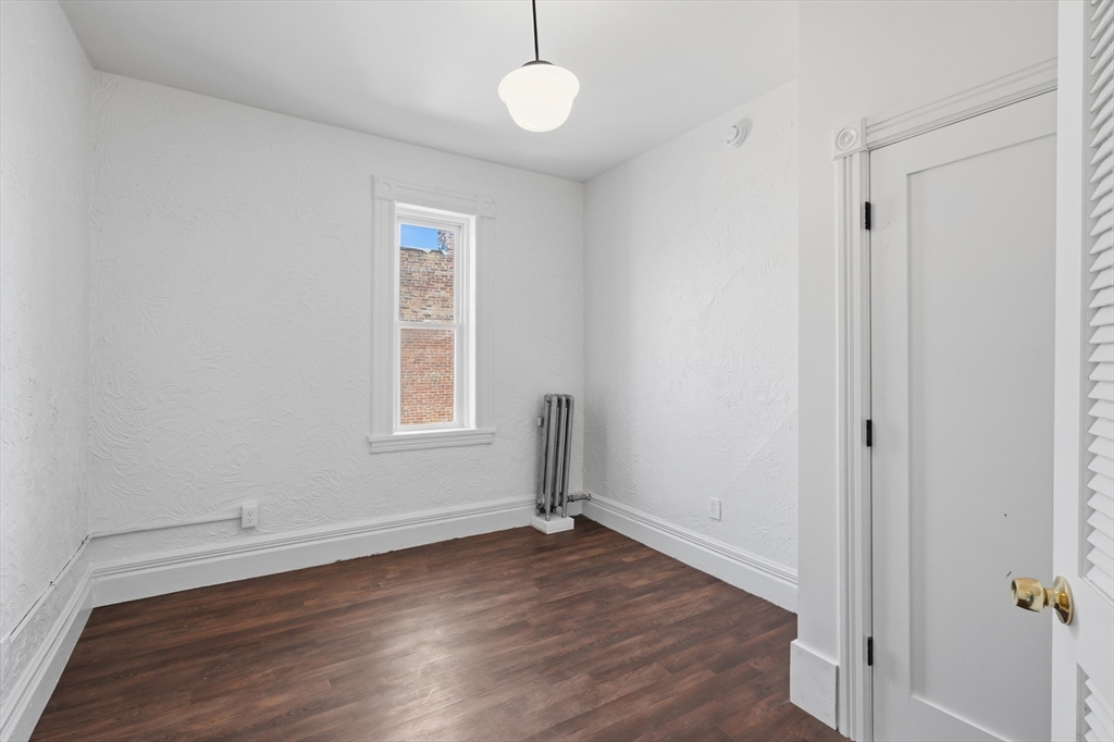 105 High Street, Unit 4P Holyoke, MA 01040 - Photo 7 of 11 an empty room with wooden floor and windows