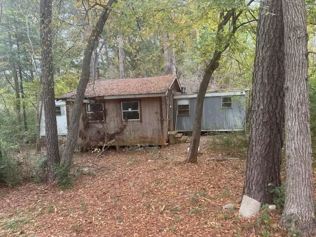 a backyard of a house with large trees and a barn