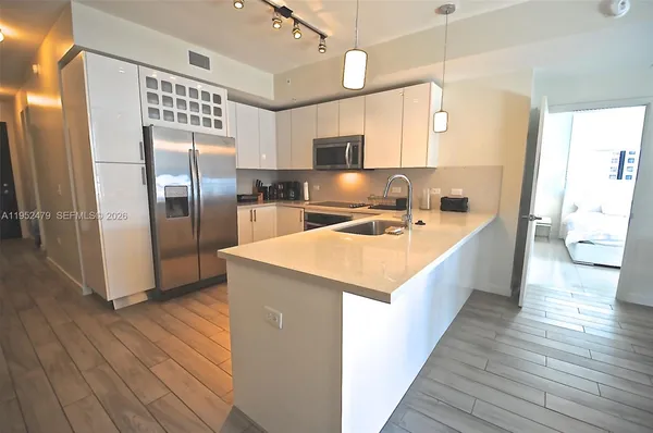 a kitchen with stainless steel appliances a sink a refrigerator and wooden floor