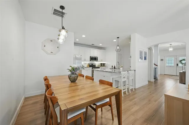 a view of a dining room and livingroom with furniture wooden floor a chandelier