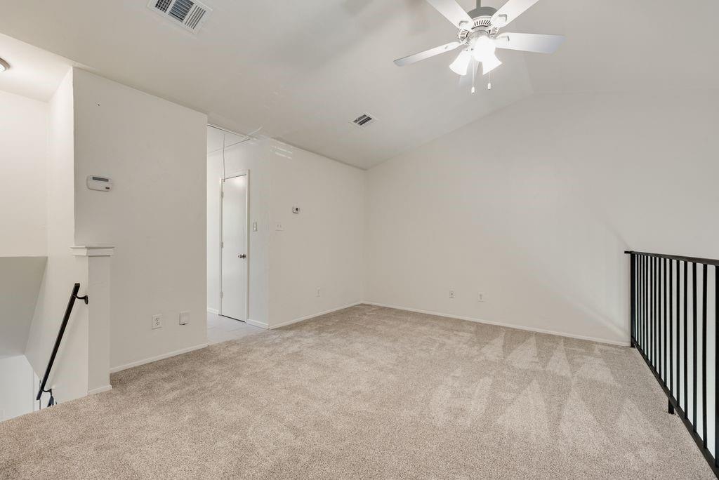 28 Abbey Road Euless, TX 76039 - Photo 15 of 19 Carpeted loft space featuring an angled ceiling, ceiling fan, and black metal railing overlooking a lower level