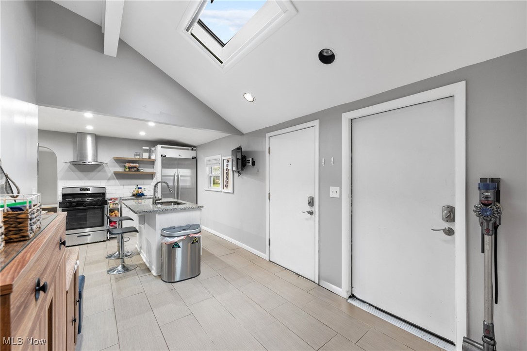 1620 Sunview Road Cleveland, OH 44124 - Photo 15 of 36 Kitchen with stainless steel appliances, a kitchen breakfast bar, wall chimney exhaust hood, a skylight, and a kitchen island with sink