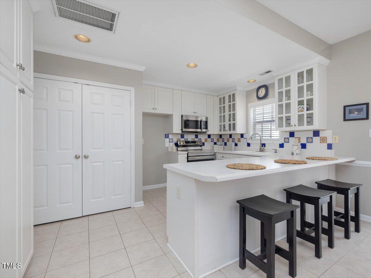 2021 Rivergate Road, Unit 102 Raleigh, NC 27614 - Photo 12 of 42 a kitchen with stainless steel appliances a sink a stove a refrigerator and island with wooden floor